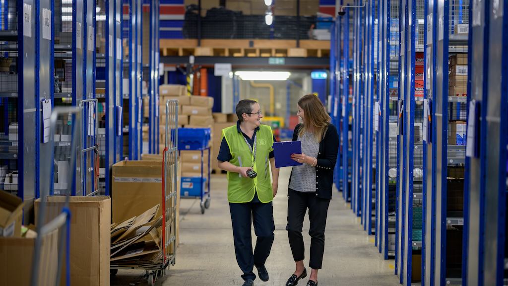 two older women walking together in a warehouse