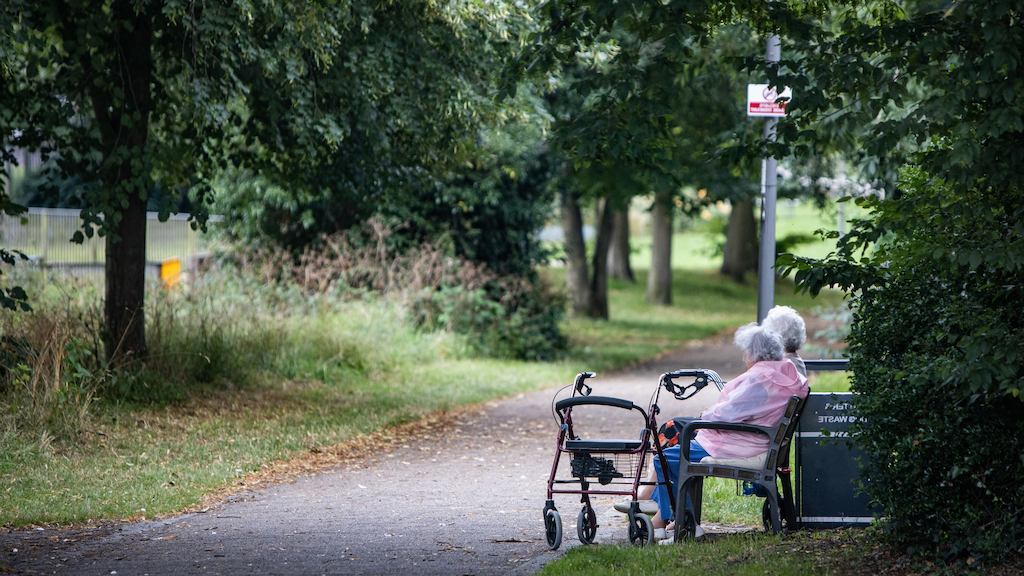 two older people sat on a bench outside