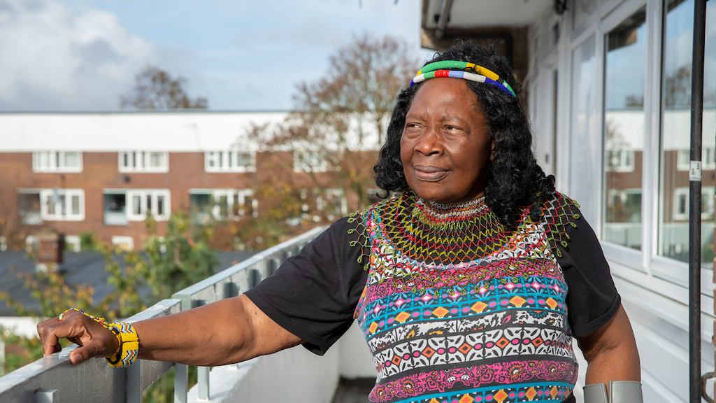an older black woman standing outside her apartment