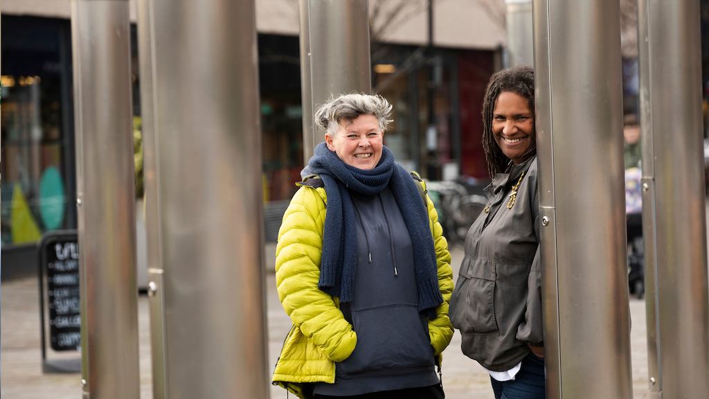 Two older women leaning against columns outside
