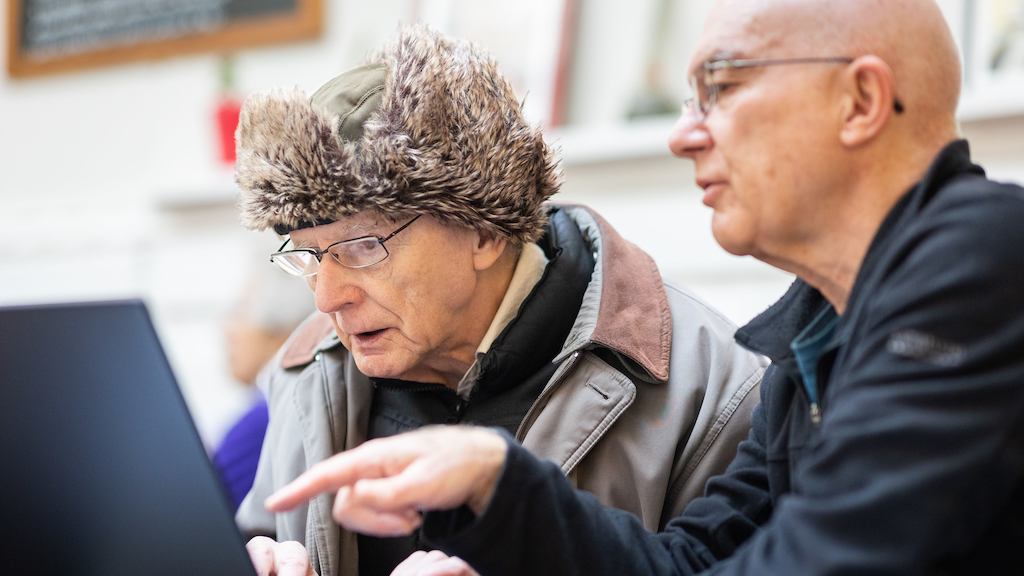 Two older men looking at a laptop