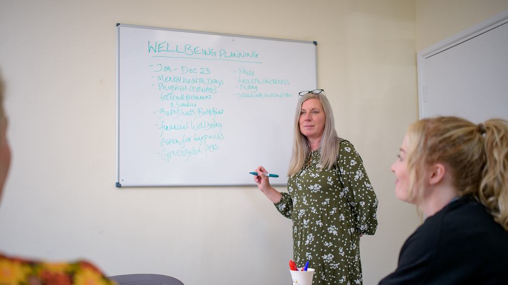 An older worker leading a meeting with a whiteboard