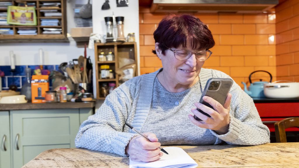 Older woman using phone in kitchen