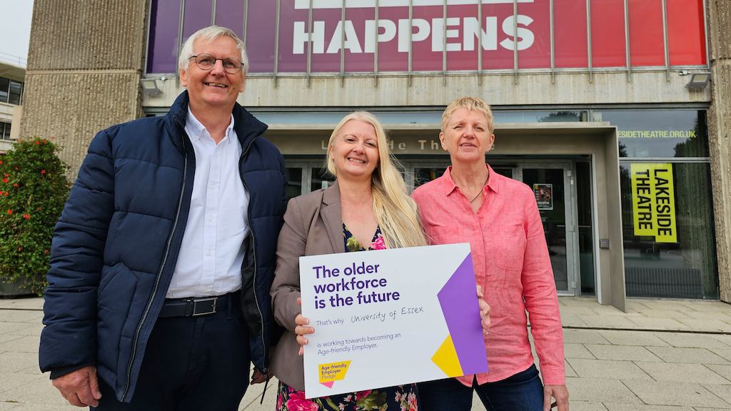 Two people outside smiling with a Pledge sign