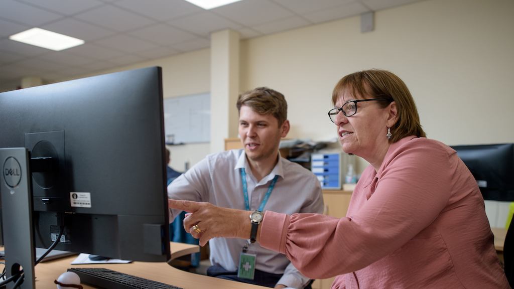 Older workers talking in front of a desktop