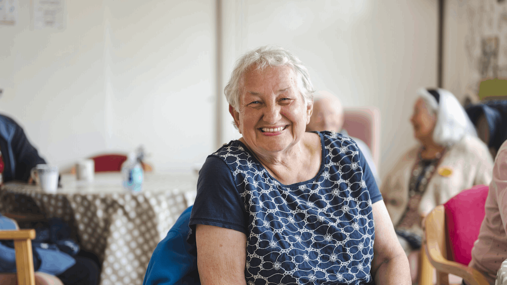 woman in a community hall smiling at the camera
