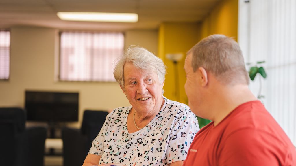 Two older people sitting down and chatting