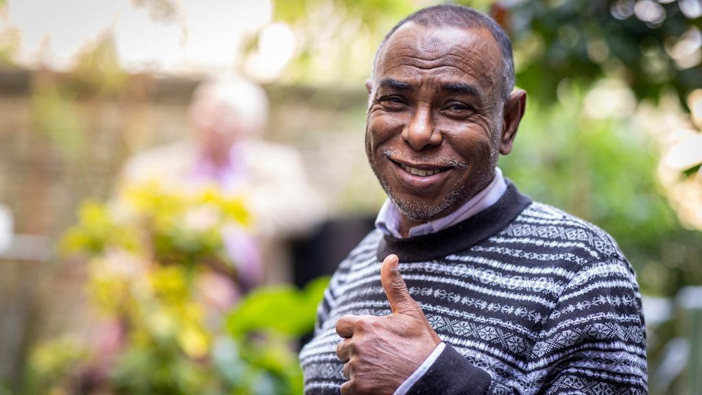 Man in a garden smiling giving a thumbs up at the camera