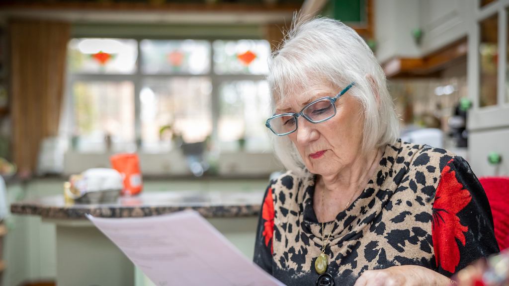 Older woman in her house reading papers