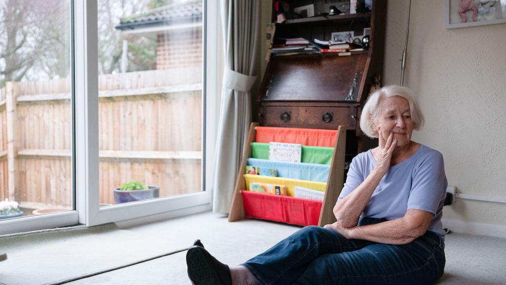 Older woman sitting on floor in her home