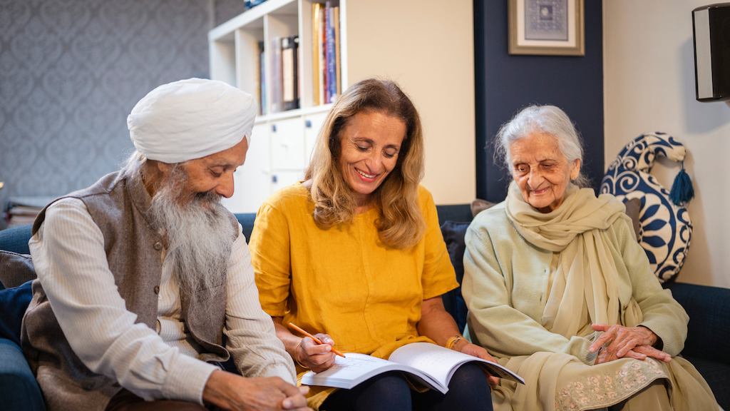 A Sikh family sitting on their sofa making planning notes in a notebook
