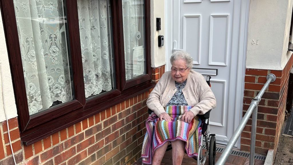 An-older-woman-in-a-wheelchair-in-front-of-her-house