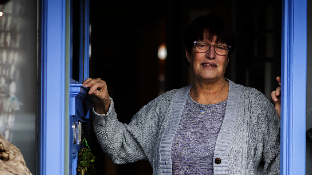 A woman stands in the doorway of her home