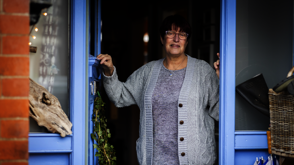 A woman stands in the doorway of her home