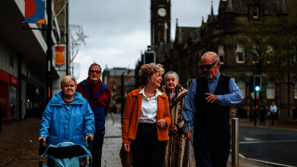 A group of older people walk down a street