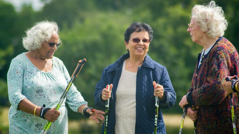 Three elderly women with nordic walking sticks.
