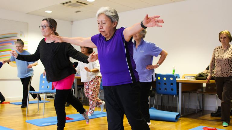 Women in physio yogalates class doing a balancing pose.