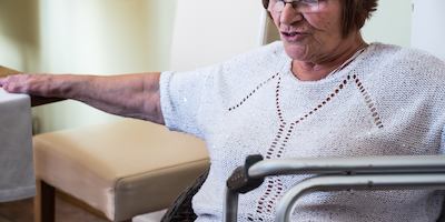 Lady sitting beside a zimmerframe