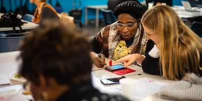 Older and younger person using phone at South London Cares workshop