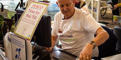 Man working at Tesco till.