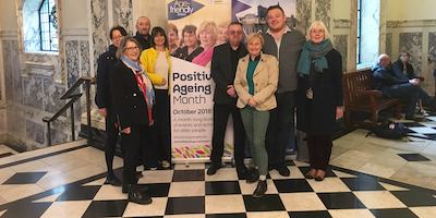 Group of people standing before a Positive Ageing Month banner.