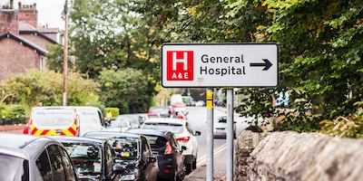 This photo is taken on the street outside of a hospital with sign saying 'General Hospital'.