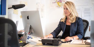 Middle aged woman seated at desk in office.