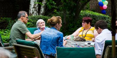 Small group of young and old people sitting at a table on a summer day.