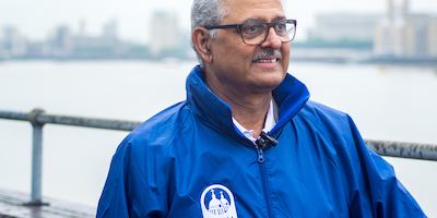 Older Asian man standing in front of the river.