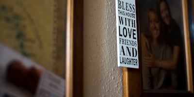 'Bless this house with love, friends and laughter' tag hanging from a family photo.