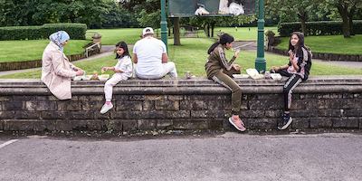 Family group sitting on a wall in a park