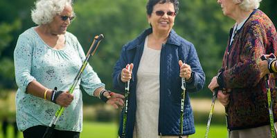 Three elderly women with nordic walking sticks.