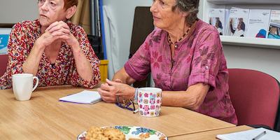 Two older women seated at a table.