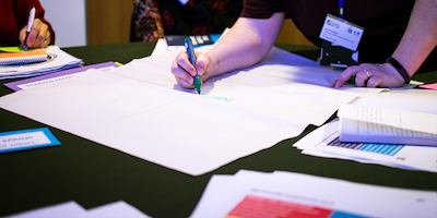 People brainstorming with pens and paper at a conference.