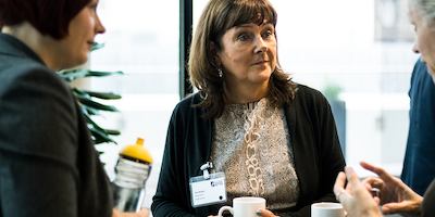 Three older women in a discussion during conference break.