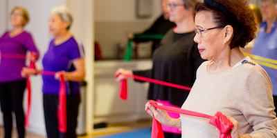 Older Asian woman using resistance band
