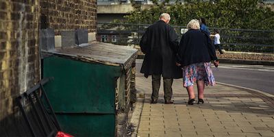 Older man and woman walking down street