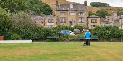 Landscape of hill and older man mowing grass