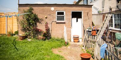 a sunny back garden that has lots of building equipment in