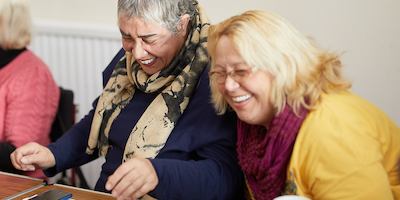 two women volunteers laughing mid-conversation