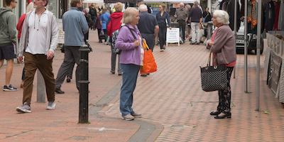 View of shoppers at a street market. Two older women having a conversation
