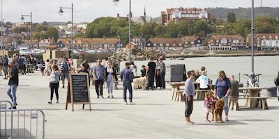 view of a sunny seaside pier with people enjoying the sunshine