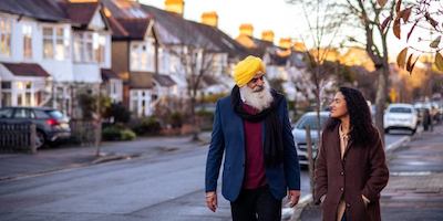 Older man and younger woman walking on street together