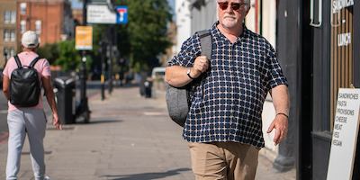 Older man walking with bag on shoulder