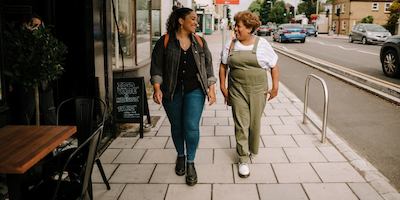 A younger woman and an older woman walk down a high street together