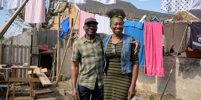 Older man and younger woman smiling in the garden in front of a washing line