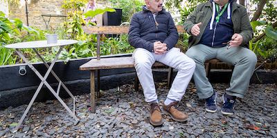 two men sitting and talking outside