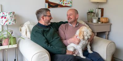 michael and his husband Johnny sitting together with their dog
