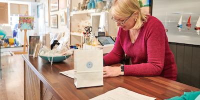 older woman filling in a form behind a till