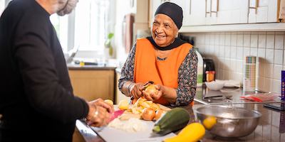 older woman chatting with a man while chopping vegetables